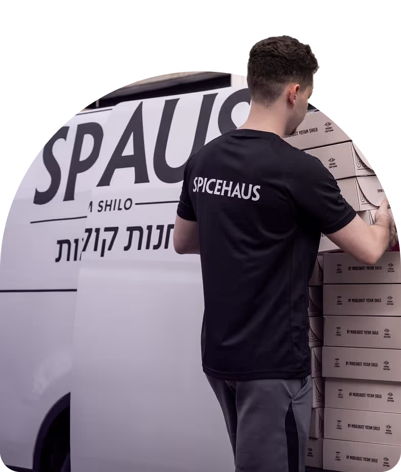 Man wearing a black SPICEHAUS shirt stacking boxes next to a SPICEHAUS delivery van.